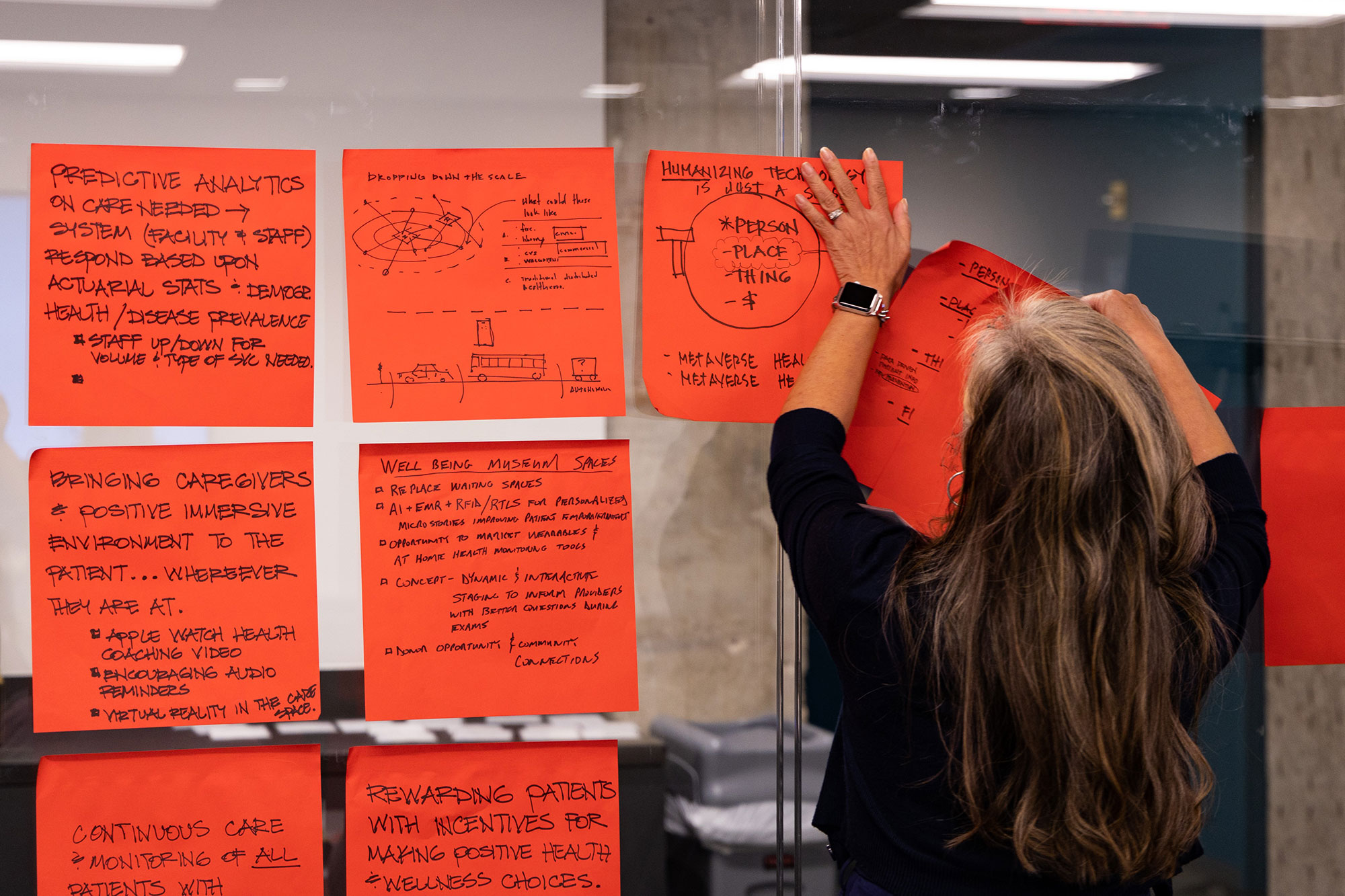 A designer hangs a poster of work on a wall